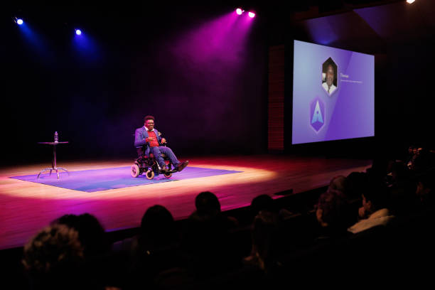 istock Man in a wheelchair giving a speech in a technology convention 1726578854
