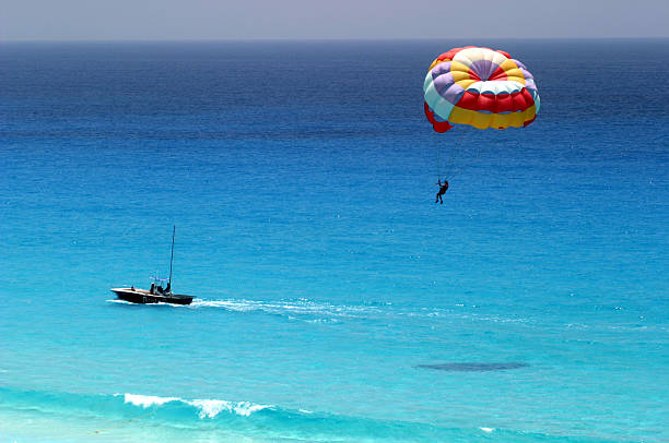 Distant shot of parasailing over ocean Parasailing in Cancun beach in summer parasailing stock pictures, royalty-free photos & images