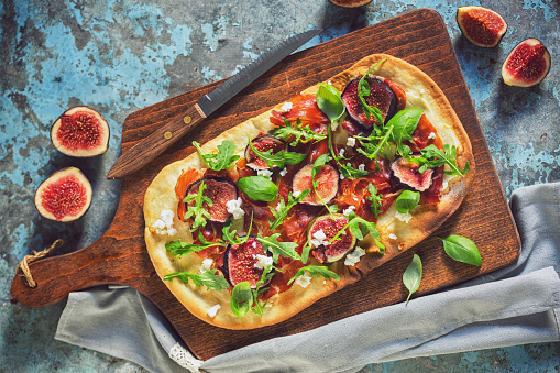 Delicious homemade pizza with figs, prosciutto, arugula and goat's cheese