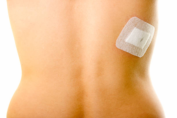 Woman's back against a white background showing a bandage stock photo