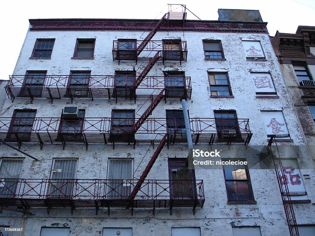 Building in Chinatown A grungy old building in New York City's Chinatown with red fire escapes. Abandoned Stock Photo