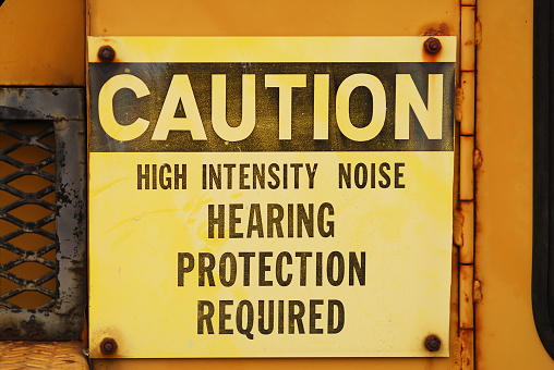 Metal caution sign for noise on industrial equipment