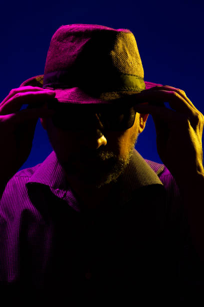 istock Mysterious serious man with a beard wearing a hat and sunglasses touching his hat. 1726595430