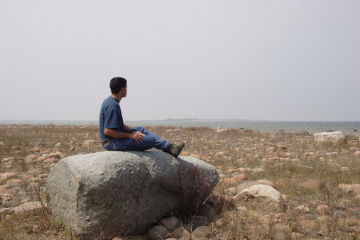 A hiker sitting on a rock overlooks the shoreline and a distant island. (Canon 20D at ISO 100.)