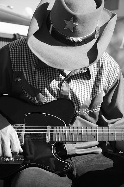 A mono photo of a cowboy playing his electric guitar