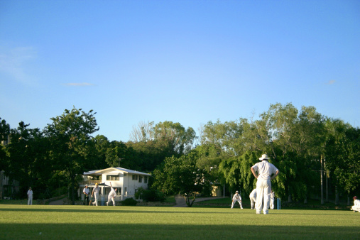 weekend cricketers at grassy oval with blue-sky background