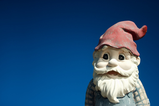 Garden gnome with red hat on a blue background
