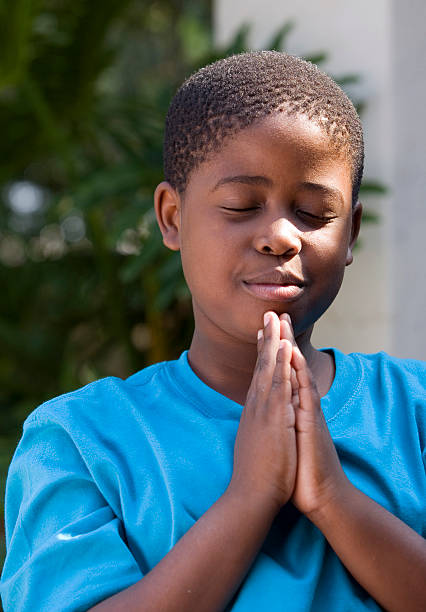 Primary schoolboy praying stock photo