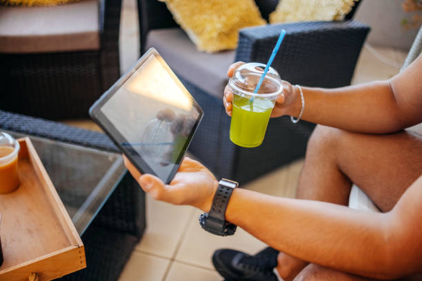 Millennial generation man holding digital tablet on balcony and having refreshment drink after exercising