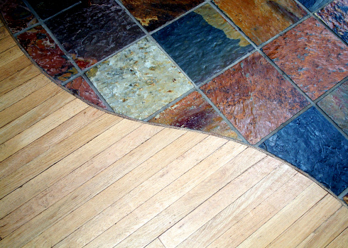 The curved junction between a Slate floor and an oak floor.