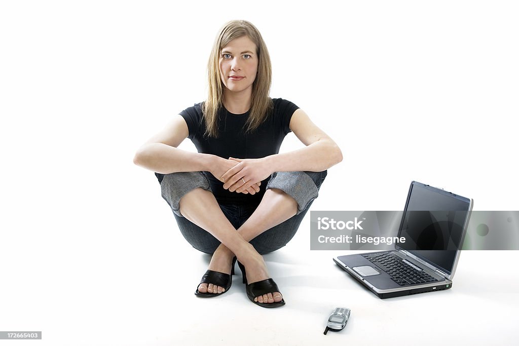 Mujer sentada junto a una computadora portátil - Foto de stock de Mujeres libre de derechos