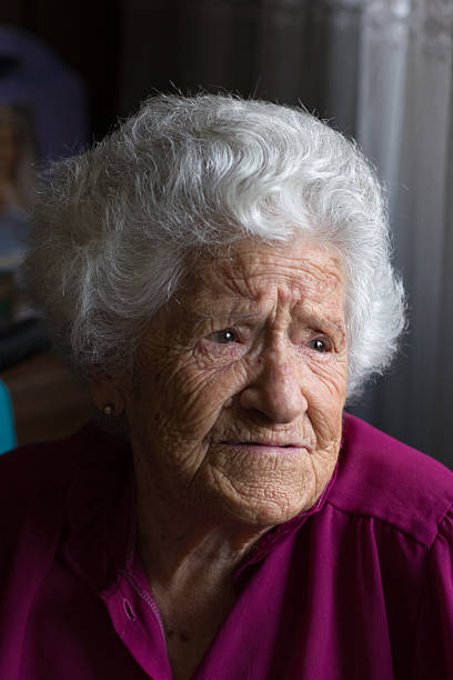 Elderly woman in window light stock photo