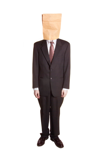 A man in business attire with a paper bag on his head.