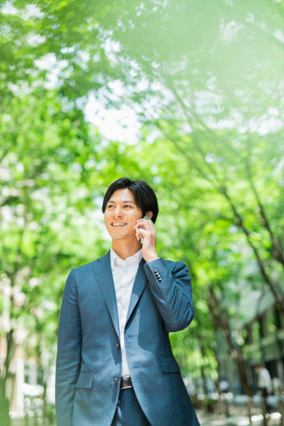 istock Young businessman walking down a street with street trees while making a phone call. 1726674067