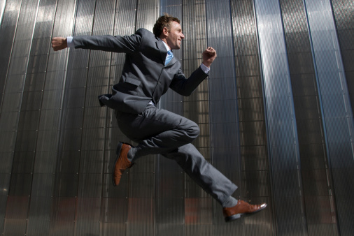 Businessman leaps into the future before a shiny textured steel background