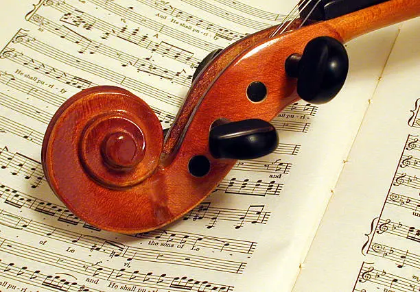 The tuning portion of a violin resting on the score of Handels Messiah