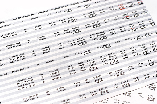 This is a picture of several spreadsheets laying over one another. The content on the spreadsheets are financially oriented: stock earnings, projected earnings and other financial information.