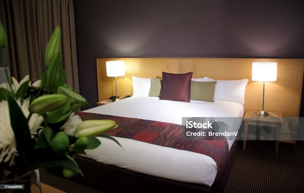 Hotel Accommodation Hotel room with flowers. Focus is on the bed. Apartment Stock Photo