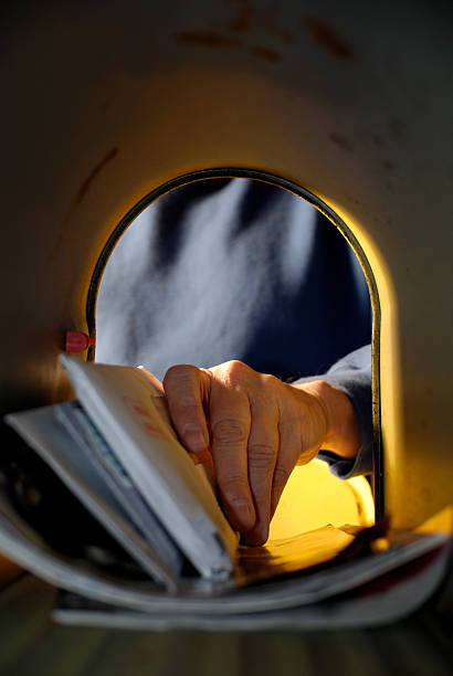A man pulling mail out of a mailbox Vertical view from inside the mail box of persons hand getting the mail. junk mail photos stock pictures, royalty-free photos & images