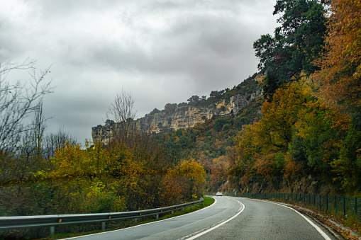Rocky cliff surrounded by autumn colors and vegetation. There is a road. Navarra, Spain.