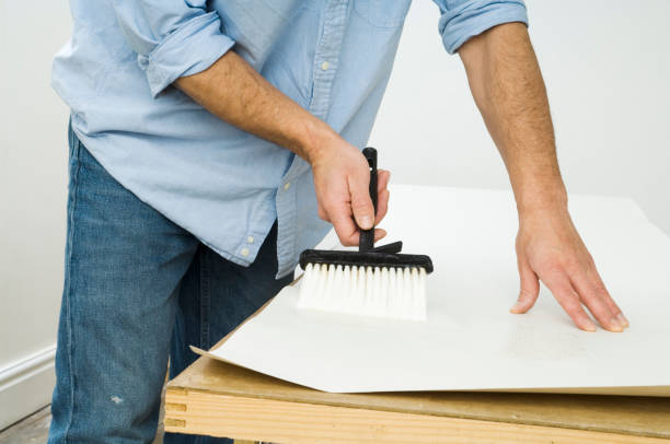 Male decorator pasting a sheet of wallpaper