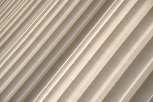 Fluted columns fill the frame in diagonal abstract full frame cream-colored background