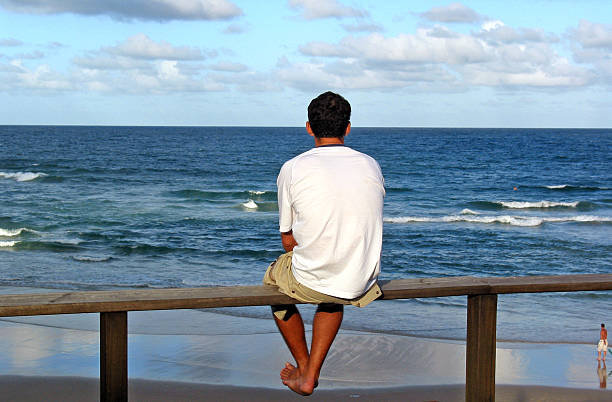 Lone man looking out to sea. stock photo