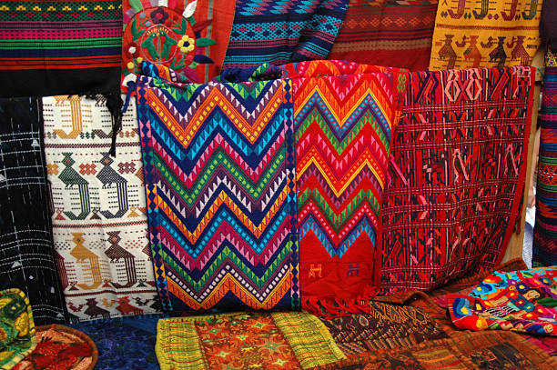 Guatemalan textiles at an open market In the popular artisan's market of Antigua, Guatemala is another layout of typical Guatemalan textiles. The far right white textile depicts the Quetzal, Guatemala national bird with it's long tail. puerto quetzal guatemala stock pictures, royalty-free photos & images