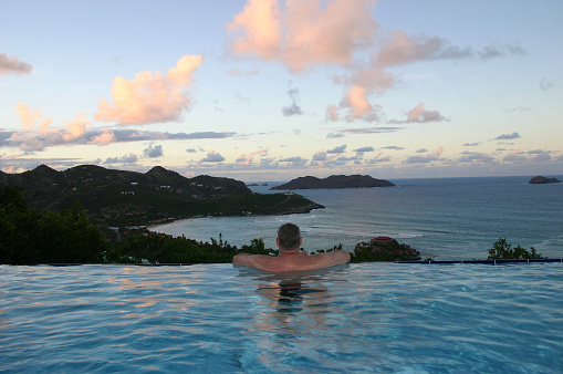 A man looks out over the ocean during the setting sun in St. Barts.
