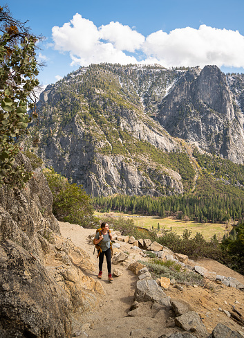 Young female hiker with a backpack climbing the trail and conquers Yosemite Valley surrounded by the amazing natural beauty of Yosemite National Park