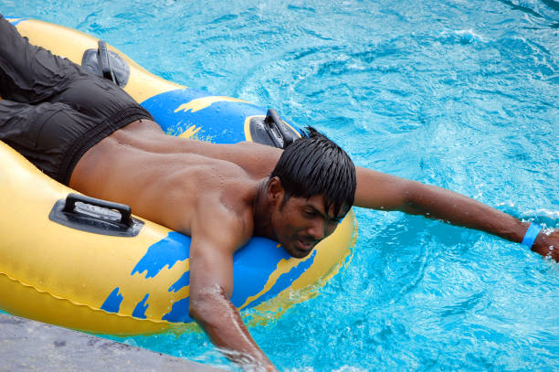 A close-up view of a multi-lane water slide in green, blue, and yellow colors. The smooth and shiny surface reflects light, emphasizing the fun and excitement of a water park attraction.