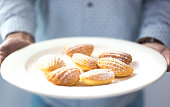 Man Holding Plate with Fresh-Baked Madeleine Cakes