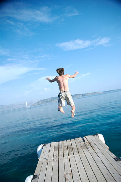 istock Young Man Jumping Off Dock Into Blue Water 172675428