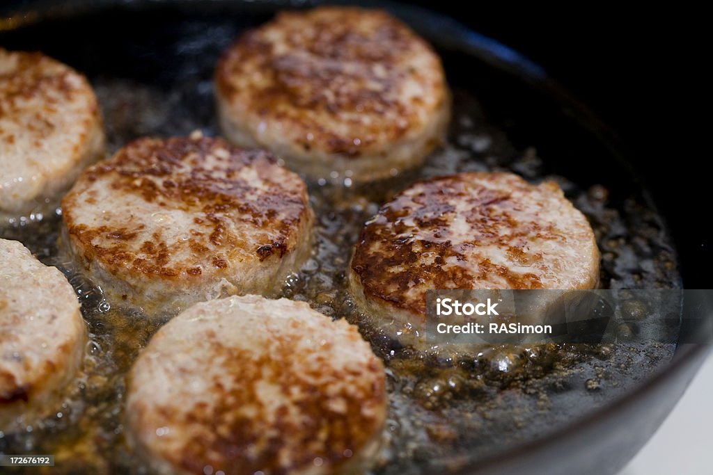 Sizzling Sausages Pork sausage patties cooking in a cast iron skillet. Breakfast Stock Photo