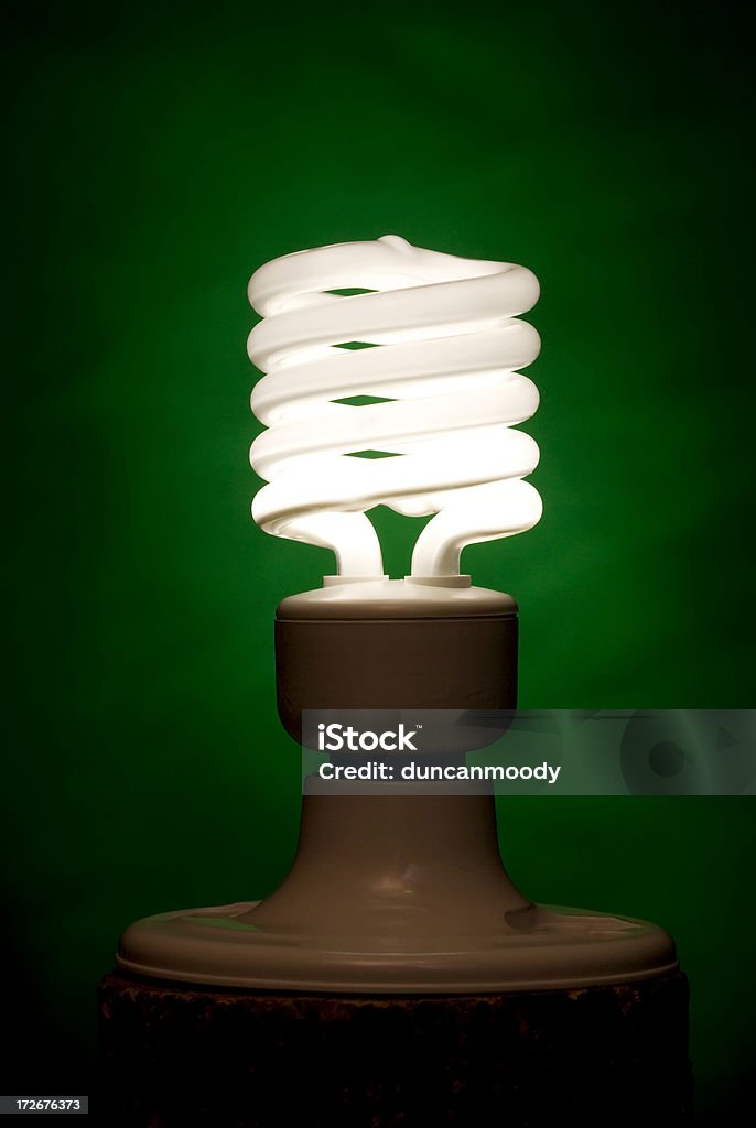 Compact fluorescent lighbulb (CFL) against green background Abstract Stock Photo