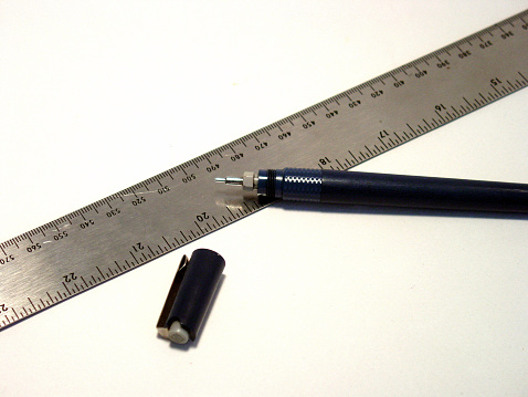 technical pen over metal ruler, on white background. 
