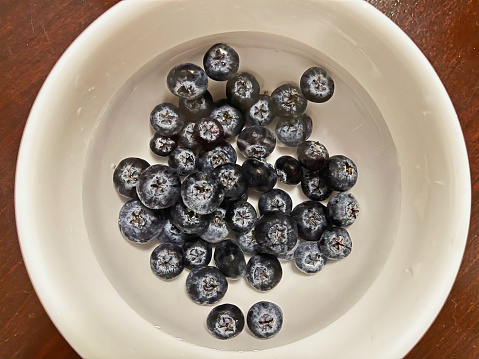 Blueberries in a white bowl with water.
