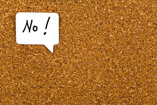 No with an exclamation mark handwritten in a word balloon. Background of a cork board.