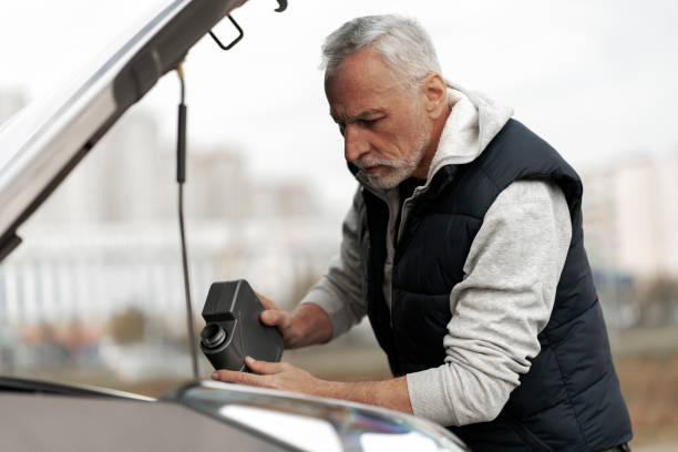60-70 세의 노인 운전자가 엔진 모터에 고품질의 오일을 붓고 연료를 보급합니다. - old men car oil 뉴스 사진 이미지