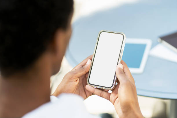 istock Young man holding mobile phone with blank white screen, sitting at workplace. Technology concept 1726800624