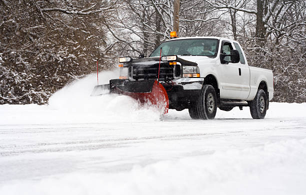 Plowing the Road Man in pickup truck plowing road during snow storm removing stock pictures, royalty-free photos & images