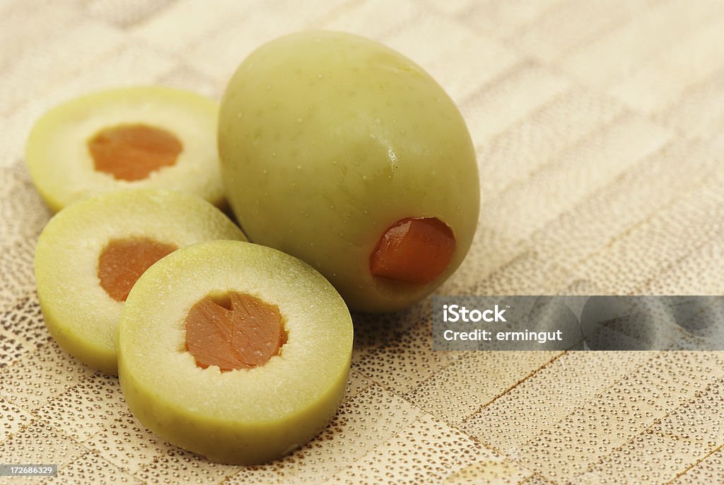 Sliced and whole stuffed olive on wooden plate Sliced and whole olive on wooden plate with interesting pattern with some copy space. Chopped Food Stock Photo