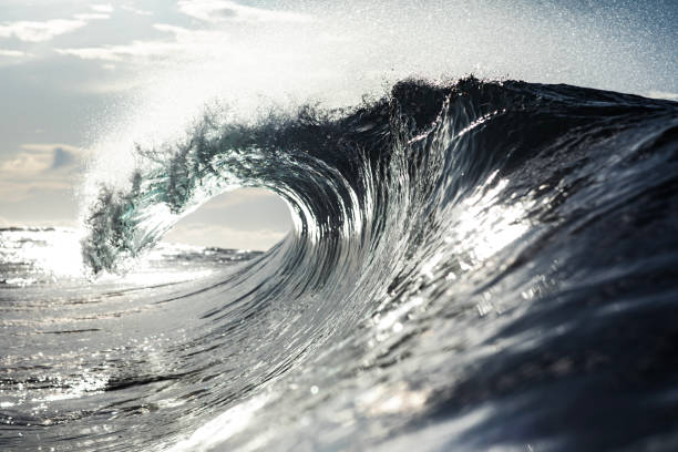 istock Close up of backlit ocean wave breaking in bright morning sunlight 1726865300
