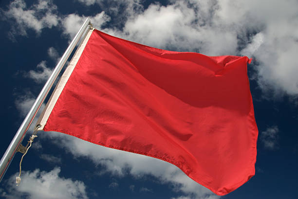 big red flag waving in the wind with the background of the blue sky and some clouds