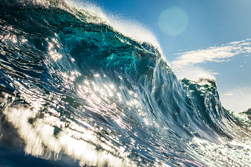 Light refractions on surface of ocean wave forming in bright morning sunlight. Photographed at sunrise while swimming in the sea off the south coast of NSW, Australia.