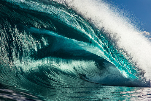 Powerful large aqua marine ocean wave breaking in bright morning light. Photographed at sunrise while swimming in the sea off the south coast of NSW, Australia.