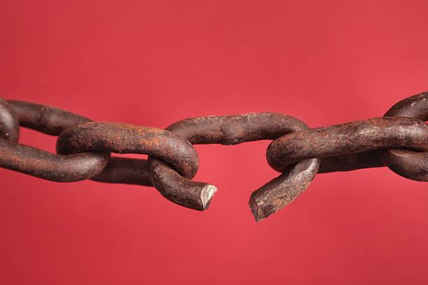Chain with broken link on red background Old rusty Chain with broken or weak link on red background. Concept of weakest link or breaking binding chains rusted chain stock pictures, royalty-free photos & images