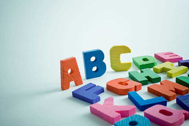 Abc Children's multi coloured wooden alphabets on blue background. spelling bee stock pictures, royalty-free photos & images