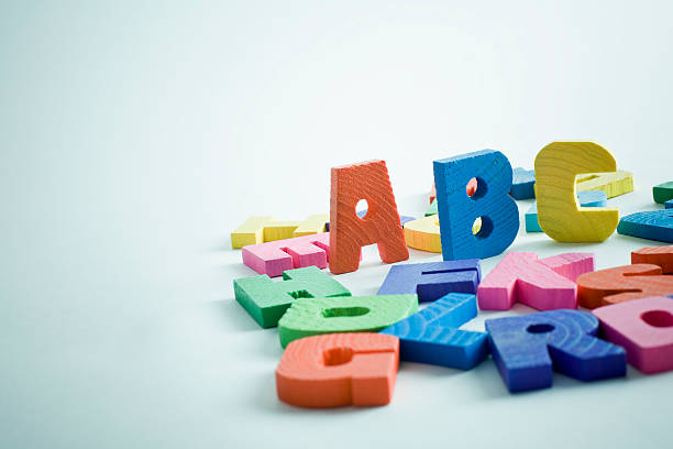 Abc Children's multi coloured wooden alphabets on blue background. spelling bee stock pictures, royalty-free photos & images