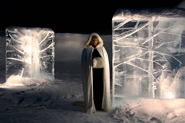 A woman in mittens etches away at an ice sculpture. 